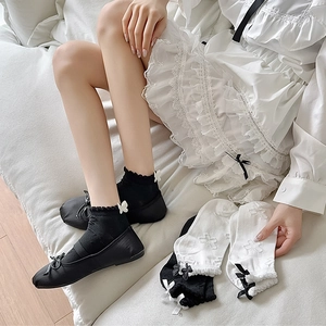 Close-up of lace-trimmed ankle socks with decorative bows paired with black ballet flats