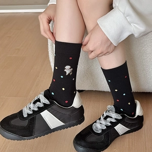 Dettaglio calzino nero in cotone con pois colorati e ricamo di un simpatico cane
