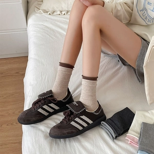 Deep brown suede sneakers with white three-stripe design and beige crew socks