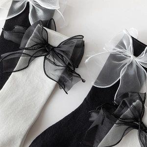 Detailed macro view of ribbed knit calf socks featuring large contrasting organza bows