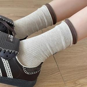 Detail of knit crew socks in beige and brown contrasting colors on wood floor
