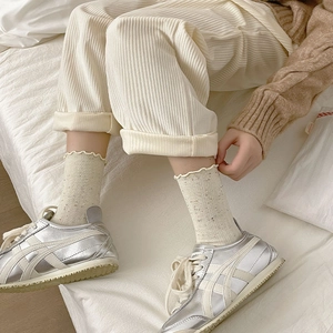 Detail of ruffled beige polka dot socks paired with silver metallic low-top sneakers