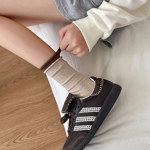 Close-up of beige rib-knit crew socks with contrast brown cuffs worn with sneakers