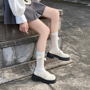 Détail de mocassins à plateforme crème avec boucle en métal et chaussettes à nœuds blancs