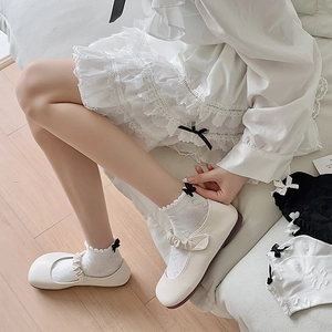 Close-up of white lace ruffle socks with black bow detail and Mary Jane shoes