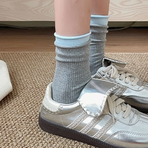 Detailed knit texture of grey crew socks with light blue double cuffs and silver shoes