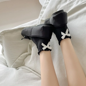 Detail of black Lolita style socks with white bow and ruffled cuffs on model
