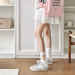 Close-up of white crew socks with cute dessert prints and casual silver trainers