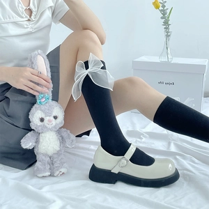 Detailed side view of knee-high black socks with oversized white mesh bows for women