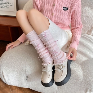 Close-up of pink knitted leg warmers with satin bows and ruffled edges in ballet style