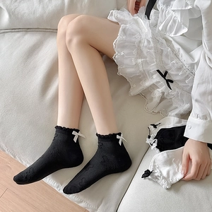 Detail of lace frill cuff and bow on cotton blend low-cut socks in black and white