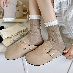 Detail of khaki ribbed crew socks with white lace trim paired with beige suede mules