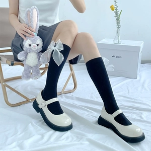 Detail of black calf socks featuring white mesh bows paired with Mary Jane shoes
