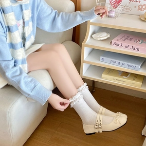 Dettaglio calze bianche con volant e scarpe Mary Jane in un ambiente in stile Lolita