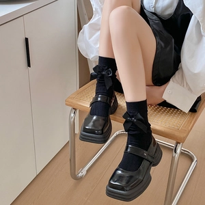 Détail de chaussures Mary Jane noires vernies à plateforme et chaussettes à nœud amovible