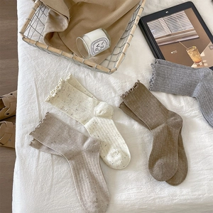 Close-up of four pairs of ruffled edge crew socks in neutral tones on white fabric