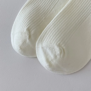 Macro shot of white ribbed knit socks showing high-quality seamless toe stitching details