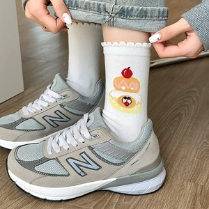 Close-up of white crew socks featuring frilly edges and cute cartoon dessert embroidery
