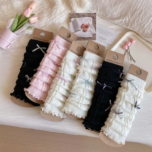 Detail view of knitted leg warmers with ribbons in black, pink, and off-white colors