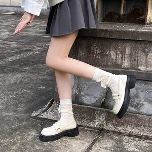 Détail de chaussettes blanches avec nœuds en satin amovibles et mocassins à plateforme