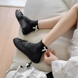 Detail of JK style black crew socks with lace trim and white satin bow on Mary Jane shoes