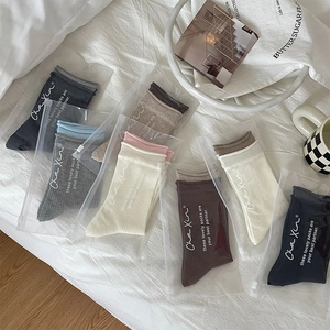 Detailed close-up of ribbed cotton crew socks in multiple neutral colors with zip packaging