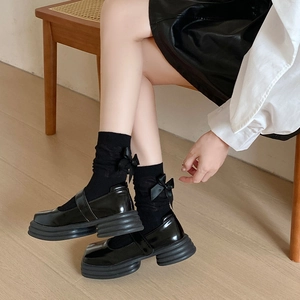 Détail de chaussures Mary Jane noires avec chaussettes à nœuds sur parquet