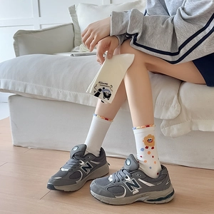 Detail of white cotton sock with cartoon bear and wavy trim worn with retro sneakers
