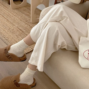 Close-up of cream ribbed socks with frill edges and brown plush buckled sandals