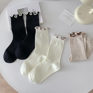 Detailed close-up of frilly edge cotton socks in black, white and oatmeal tones