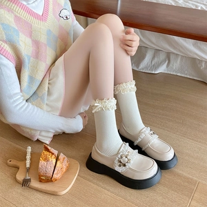 Dettaglio di calze Lolita in pizzo bianco con volant e scarpe con fibbia floreale