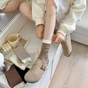 Detail of ruffled lace ribbed socks in beige and coffee colors styled with suede mules