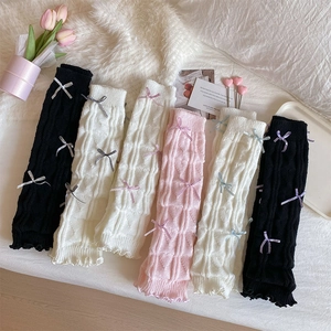 Detailed view of cable knit leg warmers with bows and ruffled edges in multiple colors