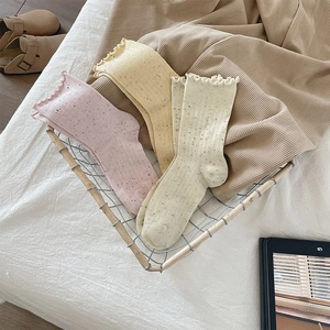 Detail of frilled hem cotton crew socks in pink yellow and cream with oat speckle pattern
