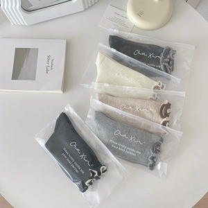 Detail of five pairs of ruffled edge cotton socks in individual zipper bags with modern decor