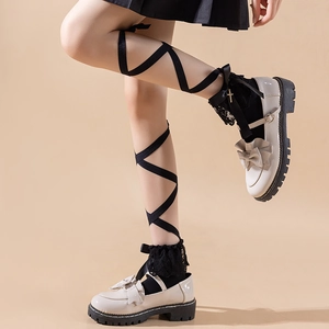 Detail of Lolita black knee-high socks with lace trim, bows, and cross charms