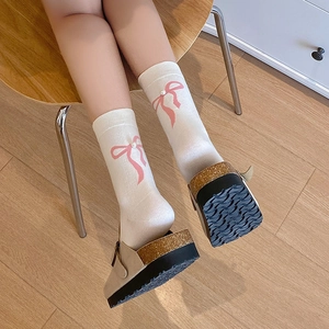 Détail de chaussettes blanches avec nœuds en ruban rose et perles de style ballerine