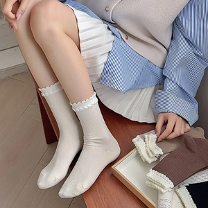 Japanese style white ribbed crew socks with elegant lace trim displayed on wooden background