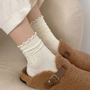 Detail of cream ruffle socks with colorful nep yarn paired with brown fuzzy mules