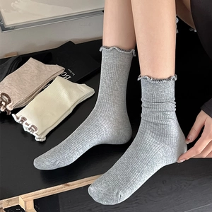 Detail view of gray ruffled edge socks featuring soft ribbed knit texture and color palette