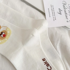 Detail shot of white cotton mid-calf sock with a cupcake and Cake text embroidery