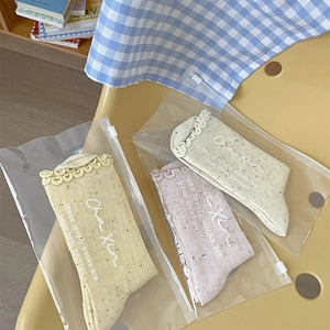 Three pairs of cotton ruffle socks in yellow, pink and beige with speckled knit texture