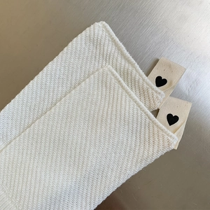 Dettaglio della trama a maglia bianca con etichetta tessuta con cuore nero minimale