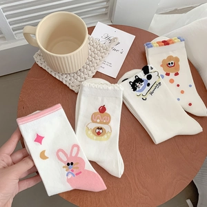 Detail of four pairs of white cotton mid-calf socks with cute cartoon animal patterns
