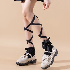 Detail of white Mary Jane shoes with black lace bow socks and ballet crossover straps