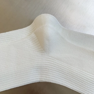 Dettaglio calzini a coste bianche in maglia con focus su cuciture del tallone e materiale