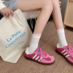 Close-up of pink suede sneakers with white stripes and matching mid-calf ballet style socks