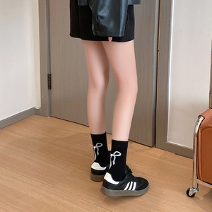 Détail de chaussettes mi-mollet noires style ballet avec nœuds et perles décoratives