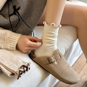 Close-up of off-white ruffled ankle socks with vertical ribbing and brown suede clogs