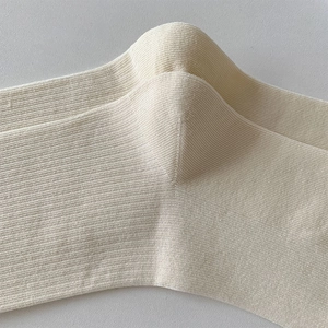 Detailed macro view of cream-white knitted crew socks with vertical ribbed texture